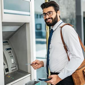 Happy man with credit card in hand ready to use ATM machine