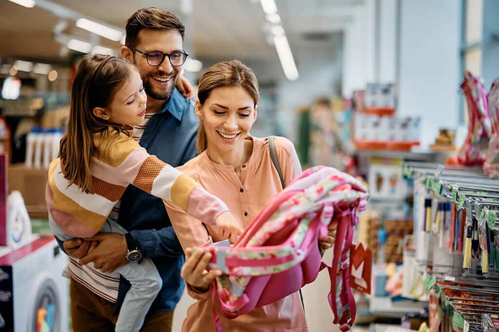 Family of three shopping in store for school bookbag.