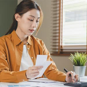 Woman working on calculator at desk.